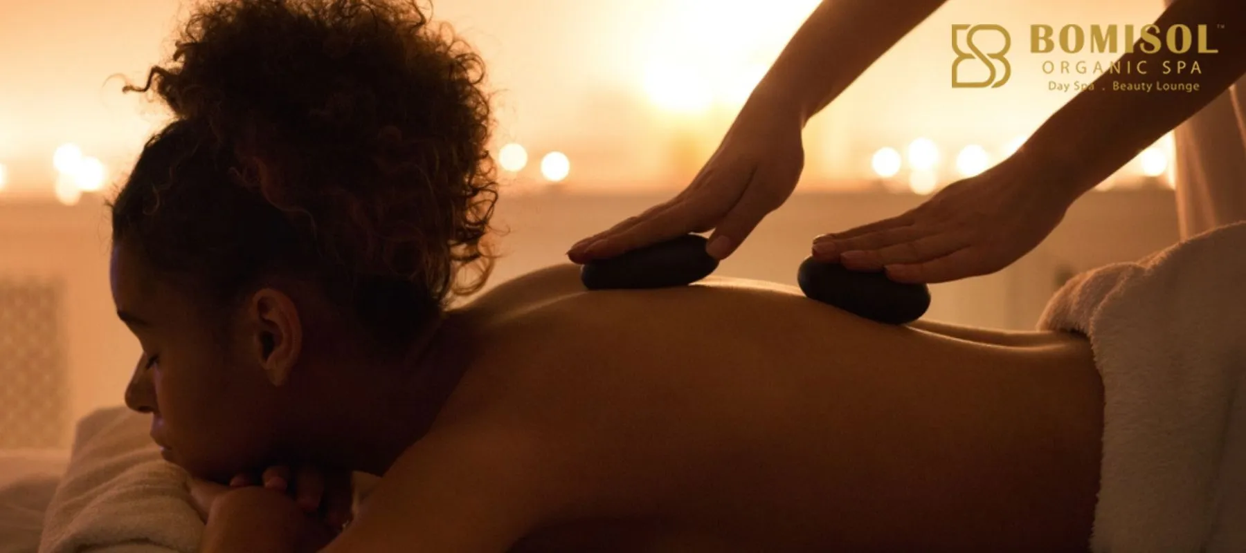 Client experiencing deep relaxation during a hot stone massage at a full body massage spa.